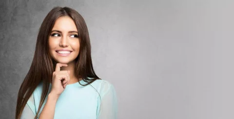 Smiling woman looking to the side with hand on chin, expressing curiosity and positivity